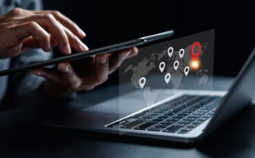 Businessman using smartphone synchronize computer searching world map with location point, GPS app, Destination travel maps and find places in the online system, searching by satellite system.